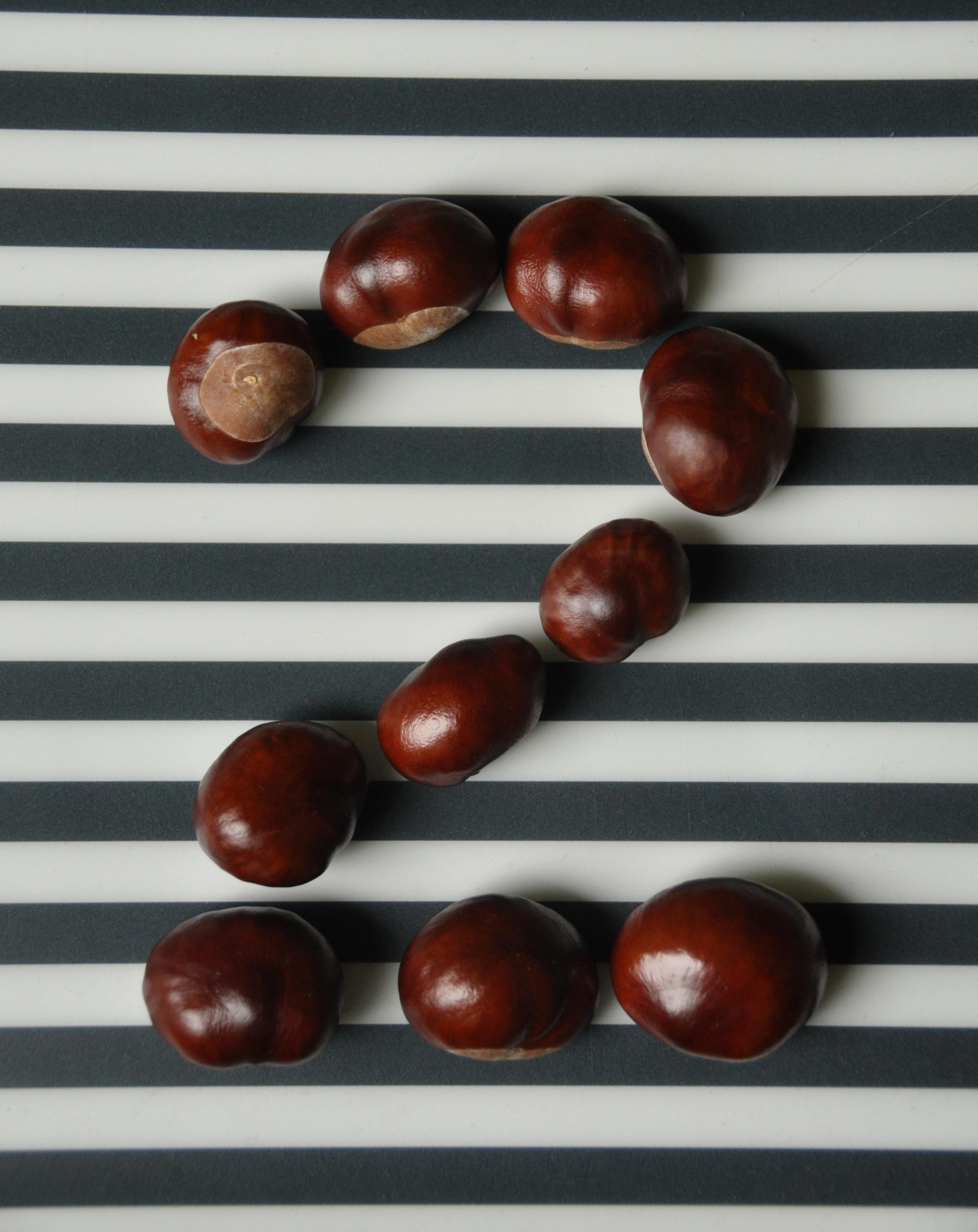 Horse chestnuts forming the digit 2 on a black and white stripted background